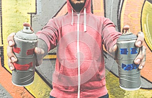 Young man drawing with two smiling sprays  - Modern art concept with urban guy performing and preparing live murales with aerosol photo