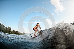Young man with dreadlocks ride the waves on surfboard.