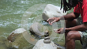 A Young Man With Dreadlocks Try to Stabilize Stack of Stones