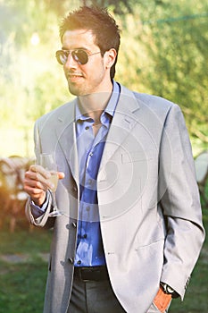 Young man with dress, sunglasses and cocktail in hand. Outdoors aperitivo party photo