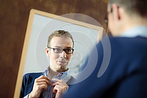 Young man dressing up and looking at mirror