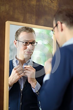 Young man dressing up and looking at mirror