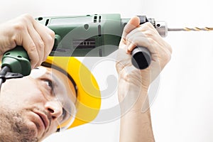 Young man drilling hole in wall