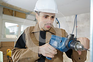 Young man drilling hole in wall