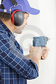 young man drilling hole in wall