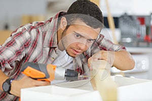 young man drilling hole into wood