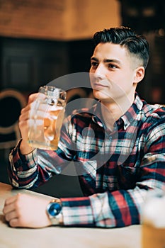 Young man drinking beer from glass at pub