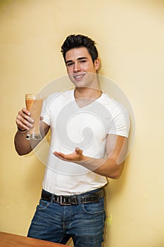 Young man drinking big glass of healthy fruit