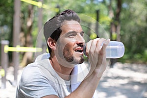 young man drinking bottle water outdoors