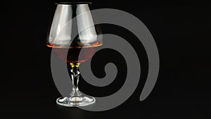Young man drinking brandy over black background