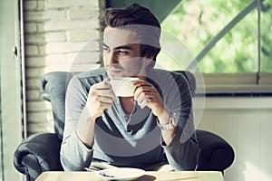 Young man drinking coffee in cafe photo