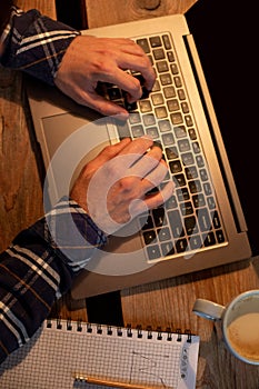 Young man drinking coffee in cafe and using laptop. Man`s hands using laptop during coffee break