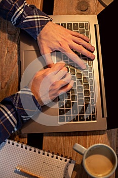 Young man drinking coffee in cafe and using laptop. Man`s hands using laptop during coffee break