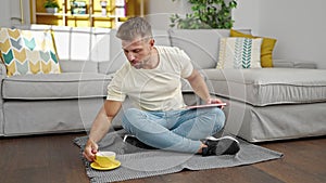 Young man drinking coffee reading book at home