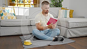 Young man drinking coffee reading book at home