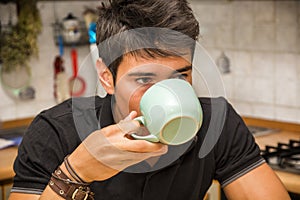 Young Man Drinking Coffee Sitting at Kitchen Table