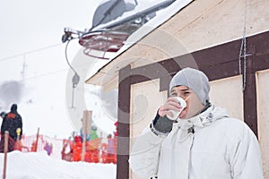 Young man drinking a cup of hot coffee to warm up