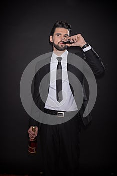 Young man drinking glass bottle alcohol suit pants jacket tie