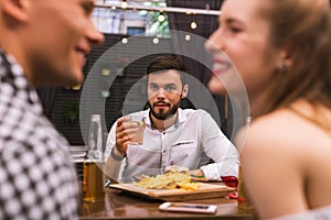 Young man drinking and his friends flirting and feeling interested