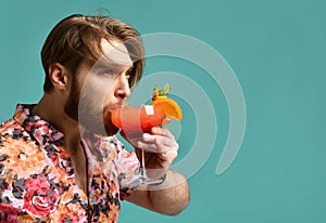 Young man drinking margarita cocktail drink juice happy looking at corner laughing over light blue mint