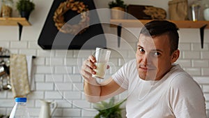 Young man drinking milk in kitchen. Adult male enjoying useful drink for breakfast.