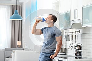 young man drinking protein shake in kitchen