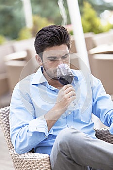 Young man drinking red wine at outdoor restaurant