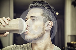 Young man drinking a smoothie drink or a protein shake