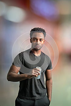 young man drinking soda holding can vertical portrait cool attitude on bokeh blur background