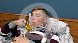 A young man is drinking tea with lemon