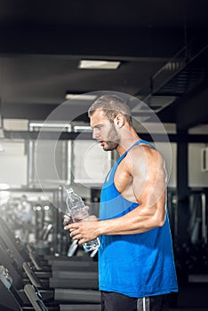 Young man drinking water in gym