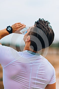 Young man drinking water, hot day