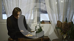 Young man drinks tea and looks at tablet in cafe. Media. Handsome young man is drinking tea alone and looking at tablet