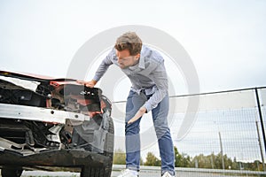 Young man driver in car accident near broken car on the road after a car accident