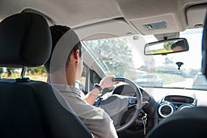 Young man driving a car, back view