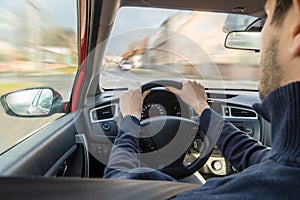 Young man is driving a car in city. Fast driving. View from interior.