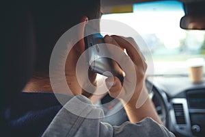 Young man driving a car with phone