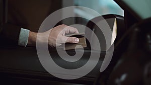 Young man driving a car, prepared a credit card for payment and holding in a hand. Car stops near the payment window.