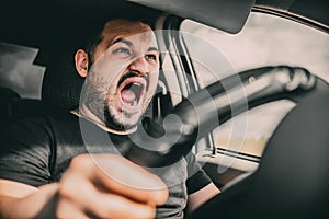 A young man driving a car in shock screams in fear of an accident