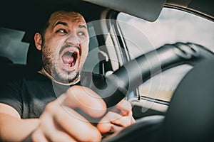 A young man driving a car in shock screams in fear of an accident
