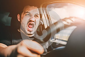 A young man driving a car in shock screams in fear of an accident