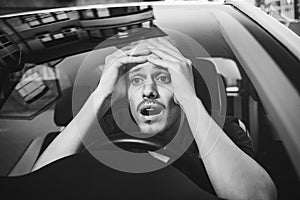 Young man driving a car shocked about to have traffic accident, windshield view.