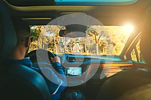 Young man driving car at sunset. Man using navigation system while driving a car