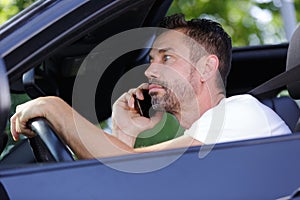 young man driving car and using mobile phone