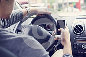 Young man driving car and using mobile phone