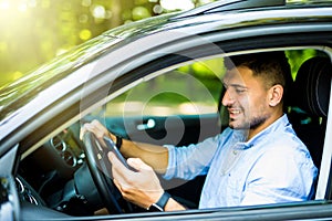 Young man driving in his car using cell mobile phone, dangerous situation