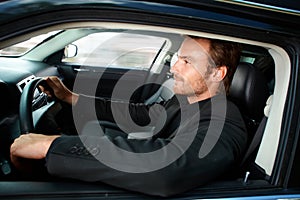 Young man driving luxury car smiling