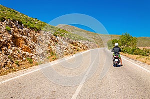 Young man driving scooter on empty asphalt road, Greek Island Kalymnos, Greece