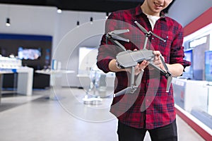 Young man in a drones store. Quadcopter in the hands. A young man buys a drone in a tech store