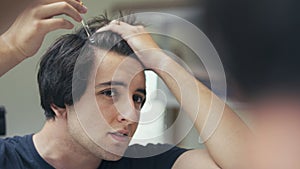 Young man dropping serum onto his hair